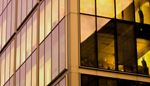 Golden hour light reflects on a modern glass building's windows,