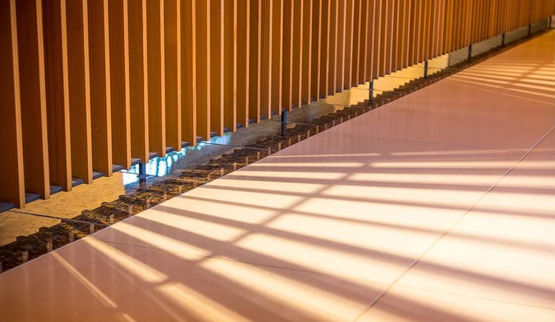 A long hallway featuring a wooden wall illuminated by a bright light, creating a warm and inviting atmosphere.