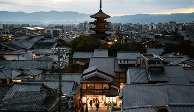 Glowing city lights and silhouettes of historic buildings under a colorful sky.