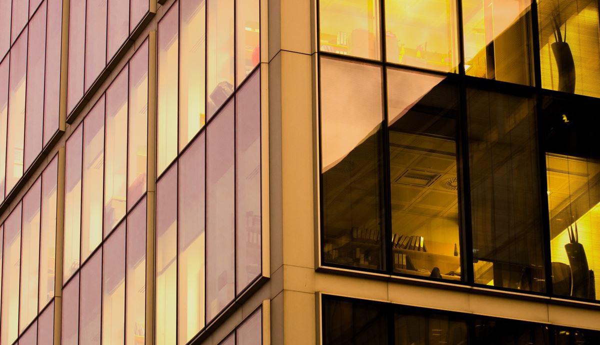 Golden hour light reflects on a modern glass building's windows,
