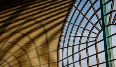 Modern architectural glass atrium with arched metal framework.